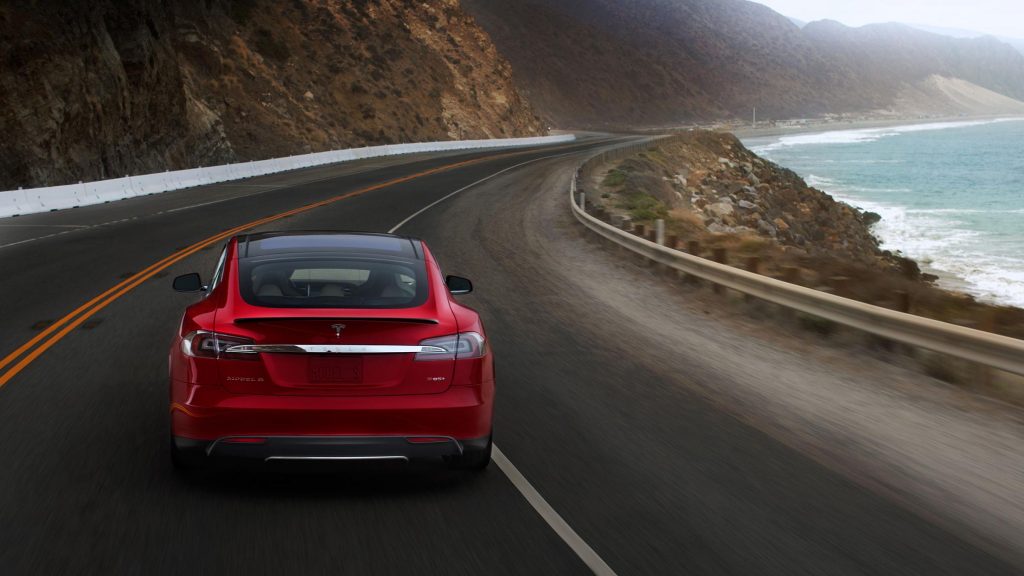 Red Tesla S85 on a California highway near the ocean. A Diminished Value Appraiser in Southern California call 772-359-4300.